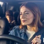 woman driving in sugar land tx with a kid in the back seat pondering rising foreclosure rates